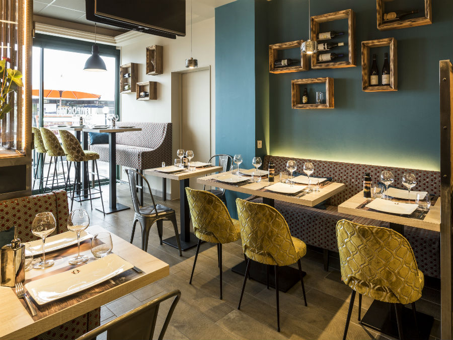 Salle de restaurant aménagée par Studio Deco, murs bleu-vert et chaises jaunes